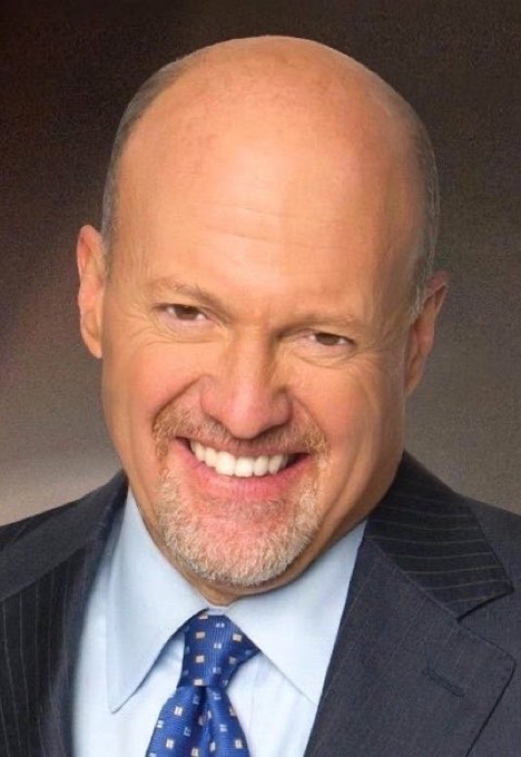 A professional headshot of a smiling, bald older man with a gray goatee, wearing a dark pinstripe suit, light blue shirt, and a blue patterned tie.