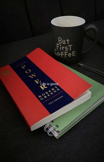 A still life shows a black mug reading 'But First Coffee' next to a copy of 'The 48 Laws of Power' by Robert Greene and a green notebook, with overlay text 'Life is good.'