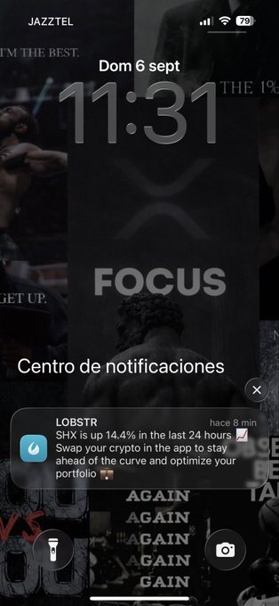 An iPhone lock screen displays the time 11:31, date 'Dom 6 sept', and a notification from 'LOBSTR' stating 'SHX is up 14.4% in the last 24 hours' over a dark 'FOCUS' wallpaper.