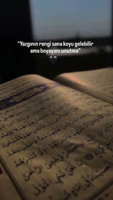 An open Quran with ornate Arabic script lies on a surface, bathed in warm light, with a Turkish quote overlaid that reads: "Yazgının rengi sana koyu gelebilir ama boyayanı unutma" accompanied by a small heart icon.