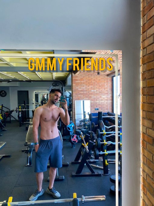 A shirtless man takes a gym selfie in a mirror, with the text 'GMMY FRIENDS' displayed in yellow at the top.