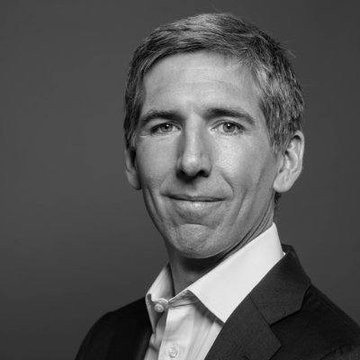 A black-and-white professional headshot features a clean-cut man in a dark suit jacket and white collared shirt, smiling subtly at the camera, matching the description of Bitwise CIO Matt Hougan. The portrait aligns with the post, serving as a professional visual for Hougan's commentary on the crypto bull market's future drivers, including stablecoins, tokenization, and institutional DeFi growth.