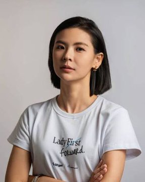 A woman with short dark hair wearing a white t-shirt that reads 'Lady First focused' posing against a light gray background.