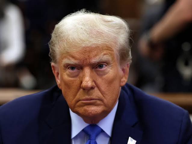 The image shows a close-up of Donald Trump, whose likeness is being used in a post criticizing the US Senate for delaying Bitcoin clarity. The post relays a CoinDesk report and expresses outrage that the US is losing ground to other countries in cryptocurrency regulation.