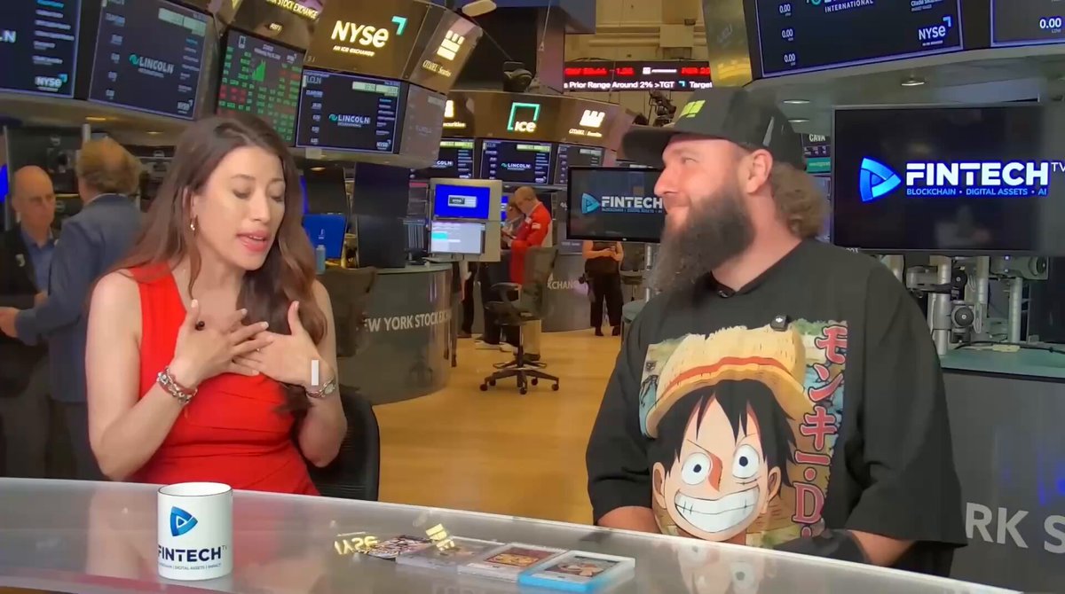 The image shows a man wearing a black shirt with a cartoon character, likely from the movie "Guardians of the Galaxy", sitting at a desk surrounded by various items such as a coffee cup, a computer monitor, and a TV screen displaying Wall Street. The scene suggests that they are having an interview or discussion about collectibles platforms on social media, specifically focusing on @solana.