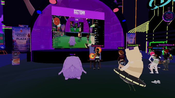 A screenshot from a virtual reality or gaming environment showing avatars gathered in front of a large screen displaying 'CREATOR PLAZA', with labels like 'Fancy', 'Climbguy123', and 'HESOYAM' visible above the characters.