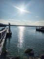 A wooden pier extends into calm, sunlit water under a bright sky, evoking the post's reflection on appreciating life's simple moments.
