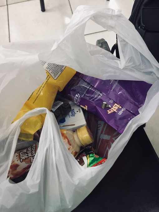 The image shows a white plastic bag filled with various items including chips, candy bars, and other snacks. It appears that someone has purchased these items at a grocery store using cryptocurrency, as indicated by the text "@AntarcticWallet". The transaction took place in just 11 seconds, making it an example of how digital payments should work - fast, convenient, and hassle-free.