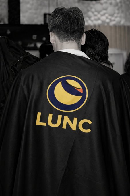 A person viewed from behind wears a black cape featuring the Terra Classic ($LUNC) logo and ticker in yellow, visually symbolizing the "bullish surge" theme of the post.