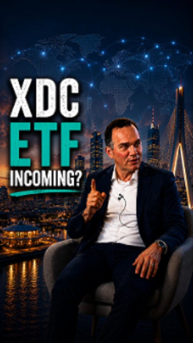 The image features an advertisement for an ETF, specifically an leveraged ETF called XDC (XDC Network). The man sitting in a chair appears to be giving a speech or presentation about this ETF. The background of the image shows a city skyline with buildings at night, indicating that it is nighttime in the city where the event took place.