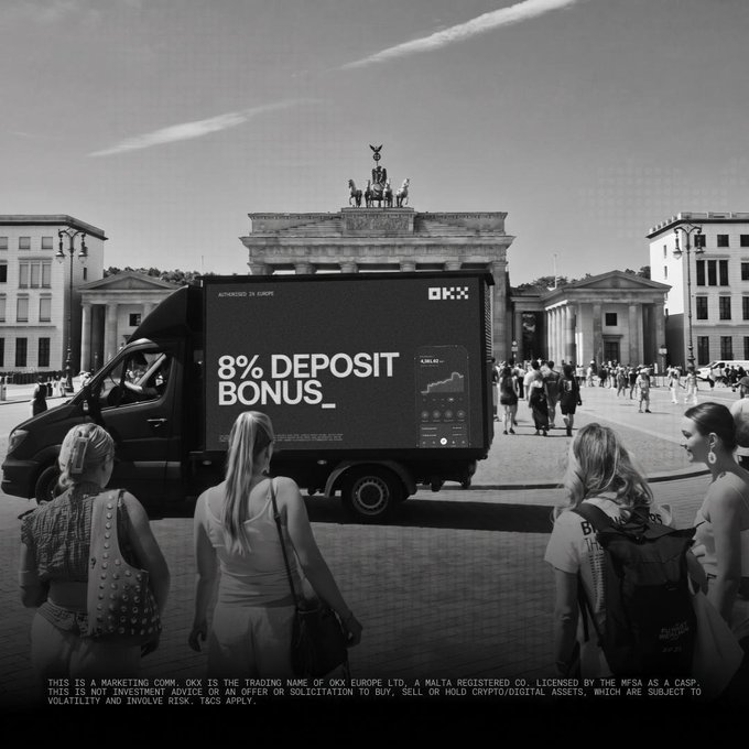 We need to write a concise 1-2 sentence caption describing what is in the image, including key text, numbers, tickers, names visible. Also note the accompanying post context about MiCA, OKX, bonuses, etc. The image shows a black-and-white photo of a truck with an advertisement in front of the Brandenburg Gate. The truck displays "8% DEPOSIT BONUS_" and "OKX" logo, "AUTHRIZED IN EUROPE". Also bottom disclaimer text: "THIS IS A MARKETING COMPANY. OKX IS THE TRADING NAME OF OKX EUROPE LTD. A MALTA REGISTERED CO. LICENSED BY THE MFSA AS A CASP. THIS IS NOT INVESTMENT ADVICE OR AN OFFER OR SOLICITATION TO BUY, SELL OR HOLD CRYPTO/DIGITAL ASSETS, WHICH ARE SUBJECT TO