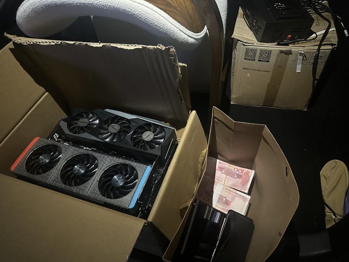 Two graphics cards are unboxed in cardboard packaging alongside a box of $100 Chinese renminbi banknotes, with the post referencing $BEM's TapeOut as an unprecedented innovation in the semiconductor/tech space. The hardware components and cash visually reinforce themes of mining or computing innovation and financial investment.