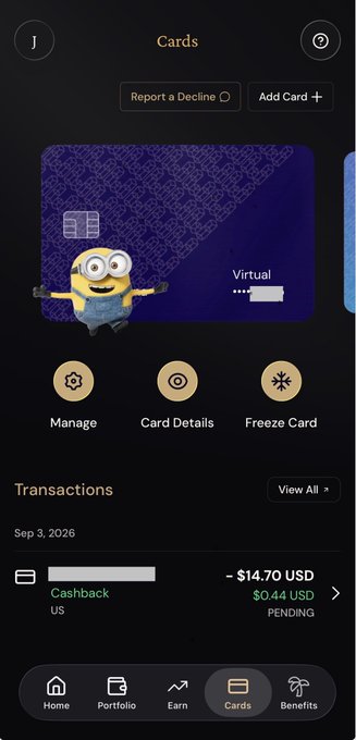 A mobile banking app screen displaying a virtual card with a Minion character design, showing a $14.70 USD cashback transaction pending and navigation options like Manage, Card Details, and Freeze Card.