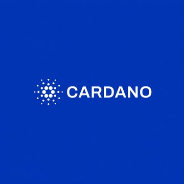 The Cardano ($ADA) logo is displayed on a blue background, accompanying news about founder Charles Hoskinson developing a new programming language to enable smart contracts on the network.