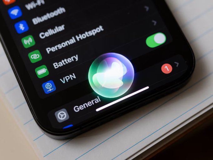 A close-up photograph of an iPhone screen showing the Settings menu with options like Wi-Fi, Bluetooth, and VPN, with the Siri interface glowing in the center.