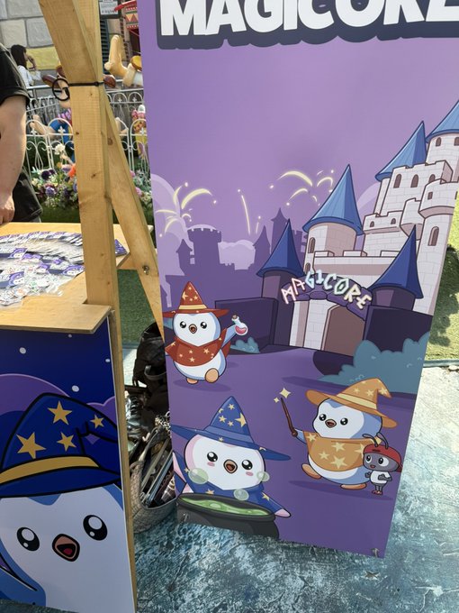 An outdoor event display features a purple banner with 'MAGICORE' branding, depicting cute wizard-hat-wearing characters in front of a castle illustration.