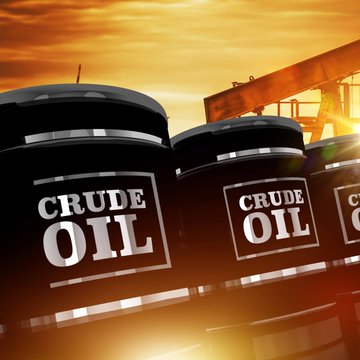 Black barrels labeled "CRUDE OIL" are stacked in front of a silhouetted pump jack at sunset, visualizing the OPEC+ output increase discussion driving the post's claim that larger supply could pressure oil prices lower and lift stocks and crypto.