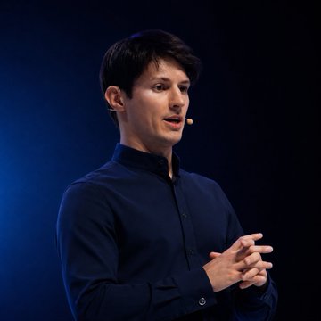 Pavel Durov, founder of Telegram, is shown on stage wearing a dark shirt and headset microphone while speaking. The image relates to the post about his announcement of Telegram's integrated non-custodial $GRAM wallet being built directly into the messaging app.
