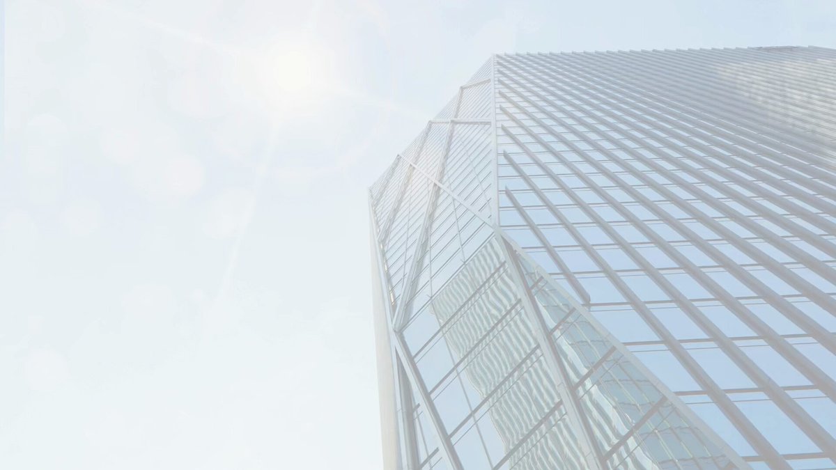 The image shows a tall glass building with many windows that reflects sunlight, giving it a bright appearance. The sun's rays are shining through the windows, creating a visually striking scene. The perspective of the photo is from below, looking up at the building, emphasizing its height and grandeur.