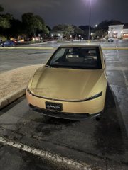 A yellow sports car parked on the street at night in a parking lot.