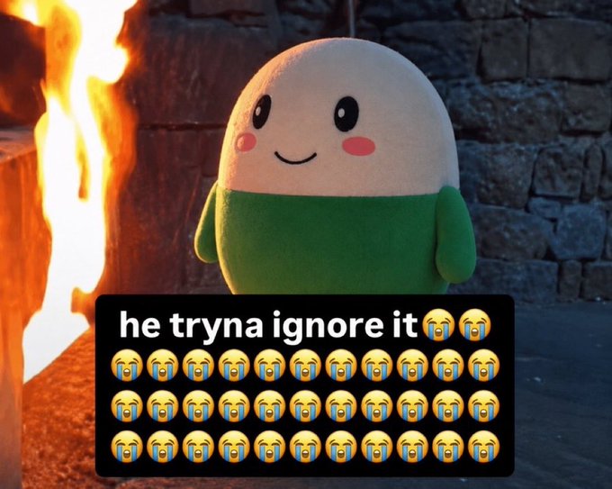 The image shows a cute plush character with a smiling face standing next to a roaring fire, with text reading "he tryna ignore it" followed by multiple crying-laughing emojis. The meme humorously illustrates the post's sentiment about how people are overlooking $CUPSEY's impressive $20 million market cap while getting excited over smaller "5-10m runners," with the plush character calmly smiling while a massive blaze (representing $CUPSEY's success) burns right next to them—capturing the willful ignorance of the situation.