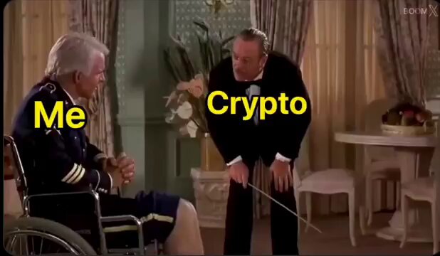 urn of flowers on a table, with "me" and "crypto" overlaid, accompanied by two men in suits in a room with white walls and gold accents.