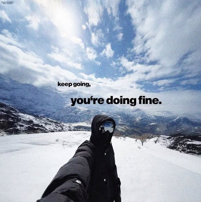 A motivational selfie showing a person in winter gear and ski goggles on a snowy mountainside with the overlaid text "keep going, you're doing fine."