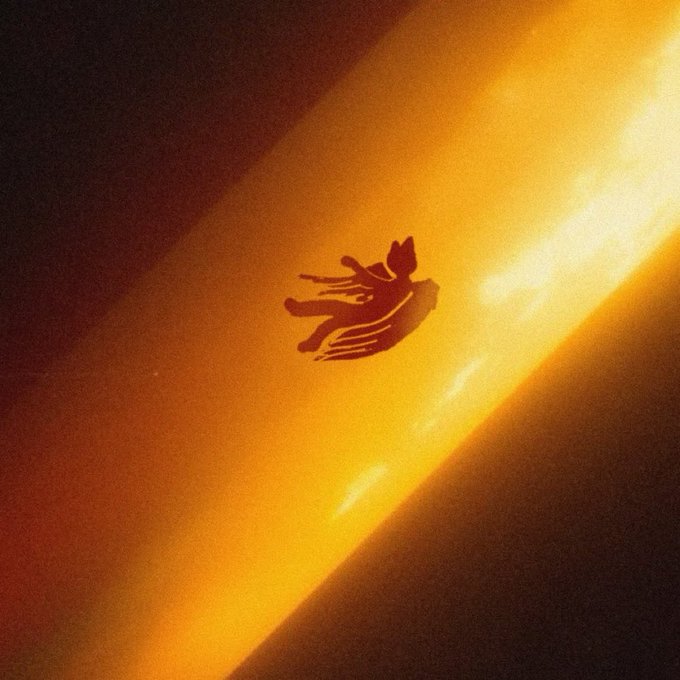 A small silhouette of a winged figure is depicted against a vibrant orange and yellow glowing background.