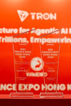 Two glass awards displayed against an orange backdrop with 'TRON' branding, recognizing 'Justin Sun' as a 'Winner' for 'Finance Expo Hong Kong' in 2025 and 2026.