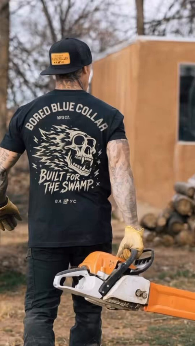 The image features a man wearing a black t-shirt with a skull design, holding an orange chainsaw. The text "Gm This is for the BORED BLUE COLLAR Boys & Girls. You know we’re BUILT FOR THE SWAMP." suggests that this post is related to a chainsaw sale or promotion. The man's attire and the chainsaw suggest he might be involved in woodworking, construction, or outdoor activities like camping.