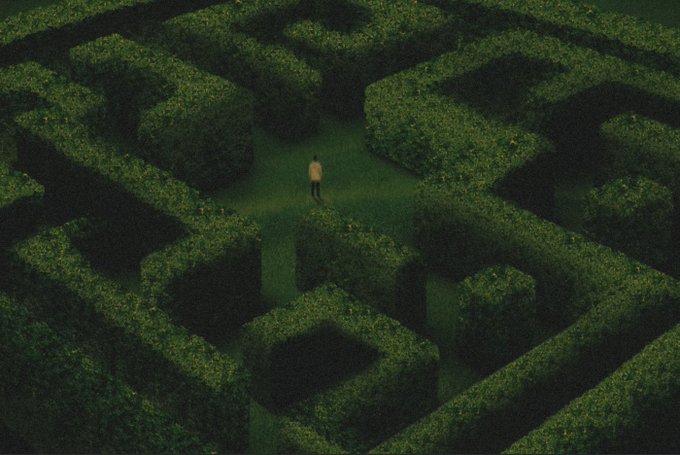 An aerial view of a solitary shirtless figure standing in the middle of a large, dark green hedge maze at night.