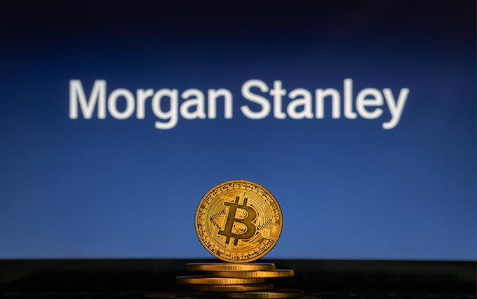 A physical Bitcoin token stands in front of a screen displaying the "Morgan Stanley" logo, visually representing the firm's expansion into cryptocurrency investment products. The image illustrates Morgan Stanley's new low-cost entry into the crypto ETP market with Ethereum and Solana offerings.