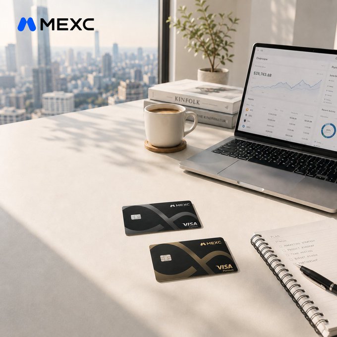 A promotional image for MEXC showing two MEXC Visa debit cards on a desk next to a laptop displaying a trading chart with a balance of $28,743.88, a coffee mug, and a city skyline visible through the window.