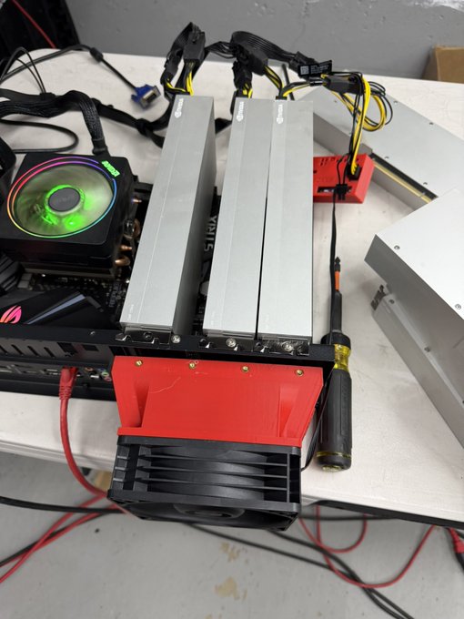 A 170HX cryptocurrency mining rig test bench featuring multiple GPUs with large silver heatsinks, a CPU cooler with RGB lighting, and an exposed red PCIe riser board setup on a workbench. The red accents on the mining frame and the visible "STRIX" branding on the motherboard components align with the enthusiast mining setup referenced in the caption.