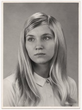 A vintage black-and-white portrait photo of a young woman with long blonde hair wearing a white collared shirt.