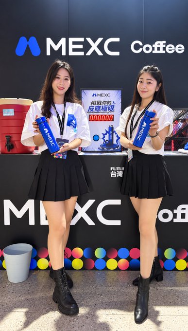 Two young women in white shirts and black pleated skirts holding blue MEXC branded cups at a MEXC Coffee promotional booth with Chinese text reading '挑戰你的反應極限'.