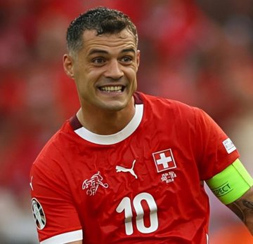 A smiling soccer player wearing a red Switzerland jersey with the number 10 and a captain's armband looks on during a match, likely connected to the high-stakes Polymarket bet on Switzerland vs. Colombia's final score avoiding 2-3.
