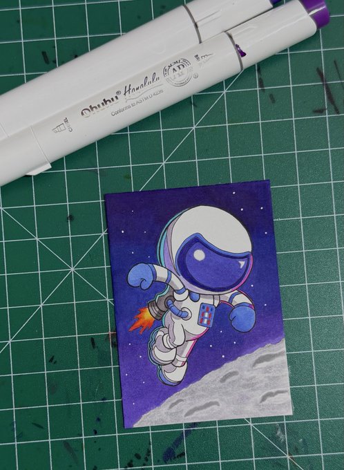 An Ohuhu alcohol-based marker drawing of an astronaut with a rocket jetpack floating above a moon surface against a starry purple sky, sitting on a green cutting mat.