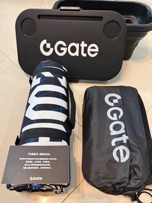 A promotional product display for 'GGate' showing a black case, a rolled-up mat with black and white straps, a black carrying bag, and a card with Chinese text that includes 'Gate' and mentions 2025.