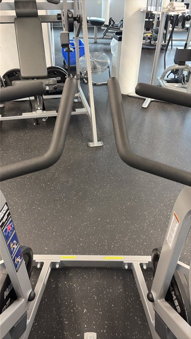 A first-person view from a piece of gym equipment, likely a treadmill or stair climber, looking out at other equipment in the facility.