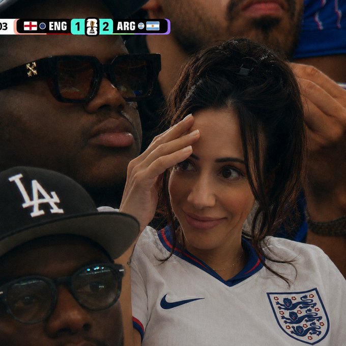 A female soccer fan wearing a white England jersey appears shocked while a man next to her sticks out his tongue, with a scoreboard showing ENG 1 - ARG 2, fitting the post's commentary about waiting for football season to begin.