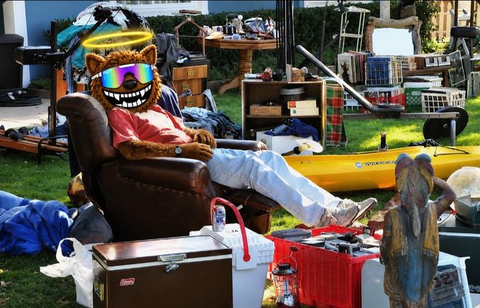 A bear mascot with a peace sign halo and reflective goggles lounges in a leather armchair amid a yard sale setup, surrounded by items including a Coleman cooler, kayak, and crates, while another Pepe-style figure stands nearby—visually representing the chaotic "selling everything" sentiment behind the $FUZZY memecoin promotion.