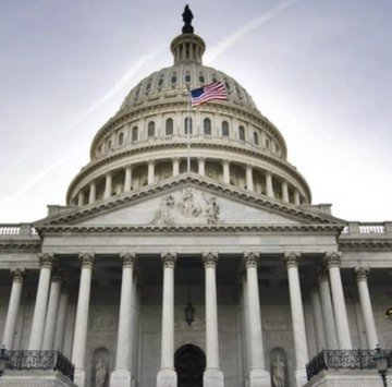 The U.S. Capitol Building with the American flag flying atop its iconic dome, symbolizing federal legislative action as Senator Cynthia Lummis pushes the CLARITY Act to end crypto regulation by enforcement and provide regulatory clarity for XRP and digital assets.