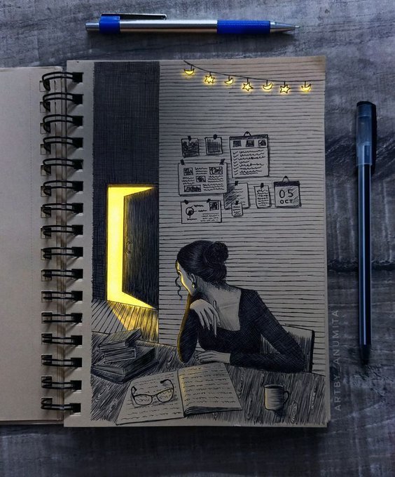 An open spiral-bound notebook on a dark surface displays a pencil sketch of a girl reading a book illuminated by a glowing yellow doorway, with a blue and silver pen resting on top and a black pen beside it; it is signed 'ART BY ARSHUTA'.