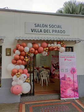 The entrance to "SALÓN SOCIAL VILLA DEL PRADO" is decorated with a peach, white, and gold balloon arch, featuring a poster for a "FIESTA COLOMBIA" event.