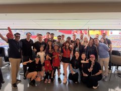 A large group photo of people posing together in what appears to be a stadium concourse or sports venue.