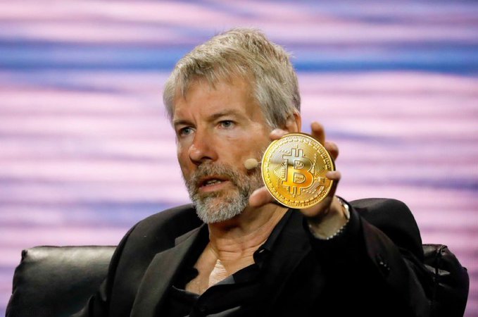 Michael Saylor holds up a physical Bitcoin token during a discussion, his remarks highlighting his belief that regulatory bodies like the SEC, CFTC, and Treasury will advance Bitcoin-friendly rules and expand institutional adoption under existing law, even without congressional action.