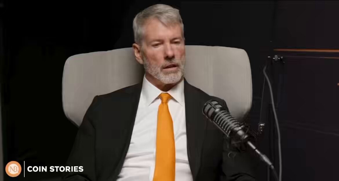 The image features a man wearing a suit, sitting in an office chair with a microphone in front of him. The man appears to be speaking into the microphone or giving advice about Bitcoin.