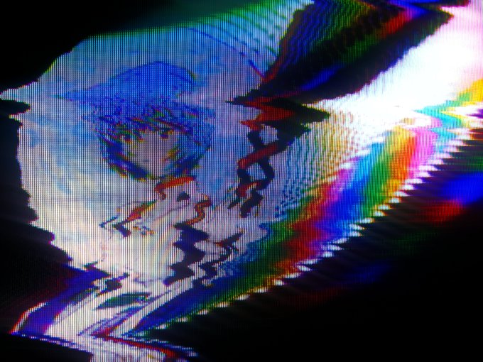 A heavily distorted, glitched image with RGB color separation and jagged visual artifacts, appearing as though a screen is failing or a digital signal is corrupted.