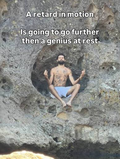 A man with a beard sits in a meditative yoga pose in a rock alcove, with text overlay reading 'A retard in motion Is going to go further then a genius at rest'.